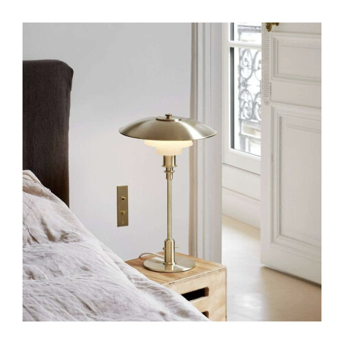 Limiterad PH 3/2 lampa med toppskärm i rå mässing på ett sängbord